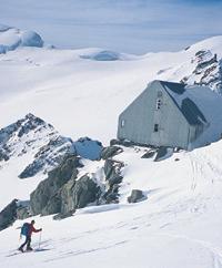 Man walking toward a high alpine hut.